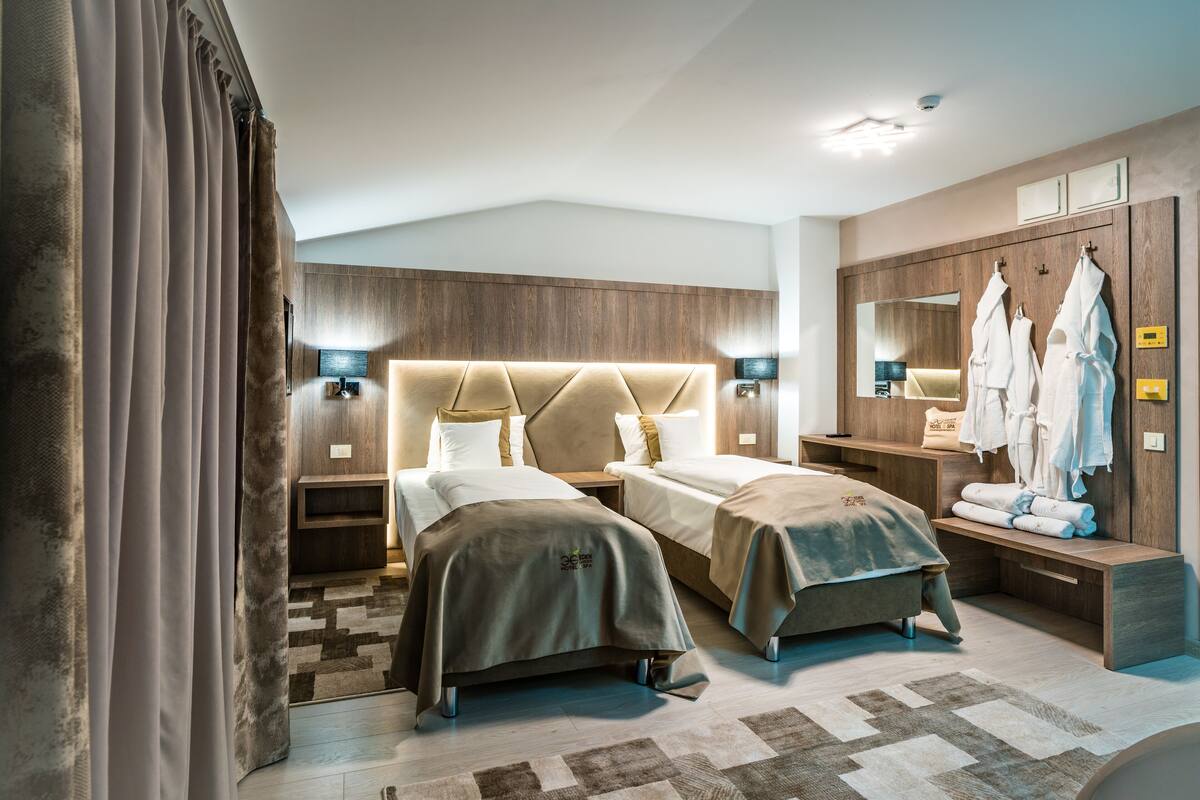 Habitación de hotel con dos camas, un espejo grande, una tocador con espejo y un armario.