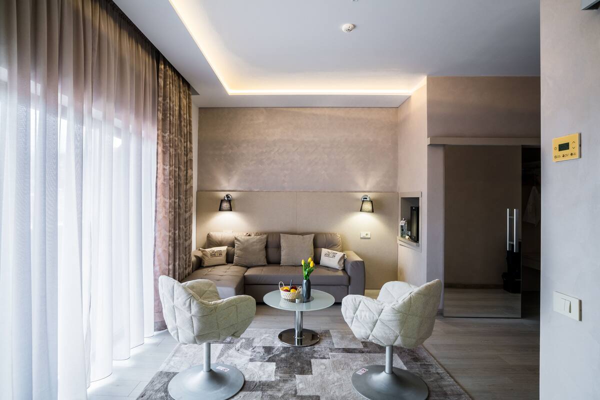 Una sala de estar moderna con un sofá, dos sillones, una mesa de centro y un jarrón con flores.