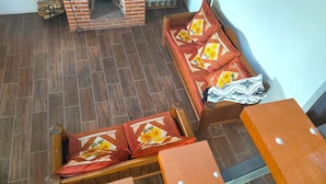 Ein Zimmer mit Kamin aus Backstein, Holzmöbeln und Fliesenboden.