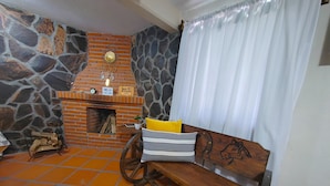 Ein gemütliches Zimmer mit Steinwand, Kamin aus Ziegelsteinen, einer hölzernen Bank und einem Fliesenboden.