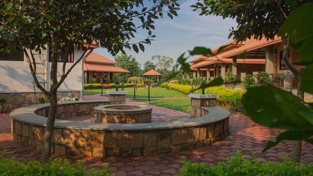 A courtyard with a circular stone fountain, a gazebo, and a well-maintained lawn. - Wildcat Tadoba Resort (Sindewahi)