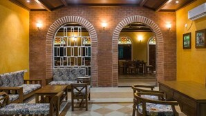 A cozy interior with arched brick walls, wooden furniture, and stained glass windows. - Wildcat Tadoba Resort (Sindewahi)