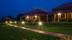 A row of three-story buildings with a brick facade and red-tiled roofs, connected by a paved walkway. - Wildcat Tadoba Resort (Sindewahi)