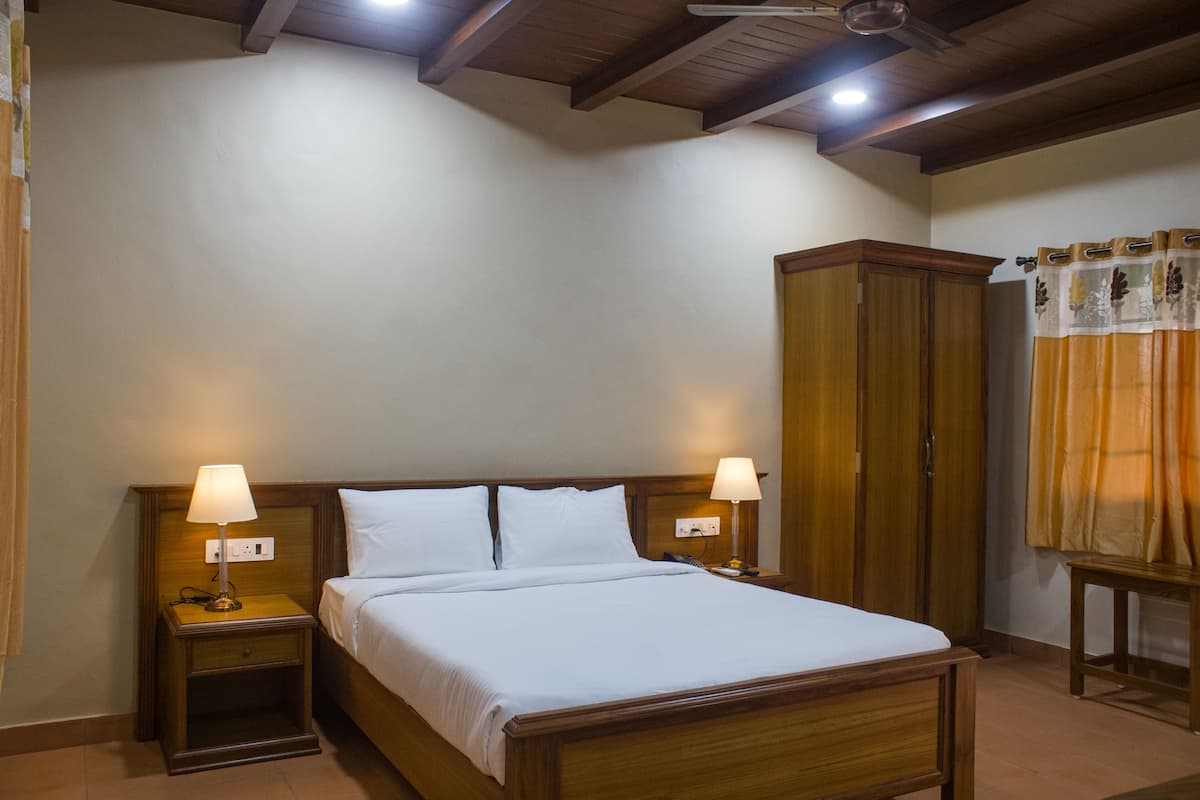 A hotel room with a wooden bed, two bedside tables with lamps, a wardrobe, and a curtain.