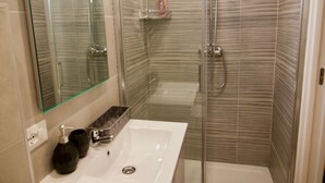 A modern bathroom with a glass-enclosed shower, a white sink, and a large mirror.