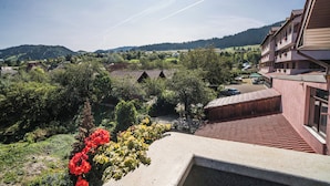 A residential area with traditional architecture, a garden with red flowers, and a view of the surrounding hills.