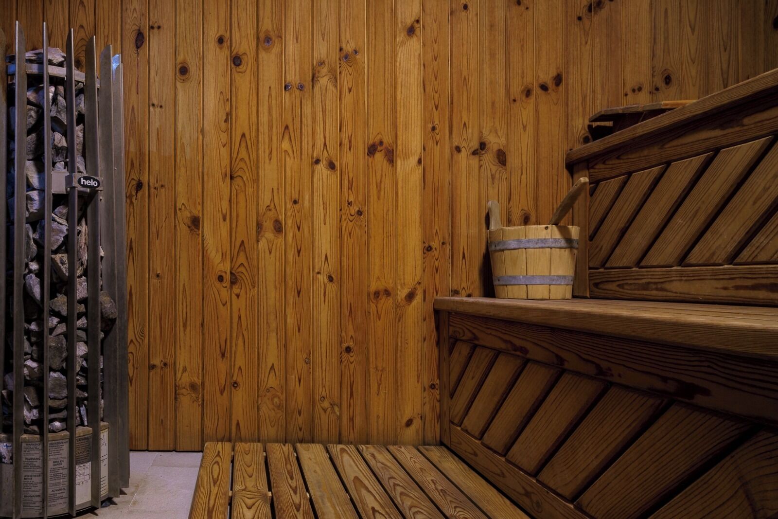 A wooden sauna with benches and a stone wall.