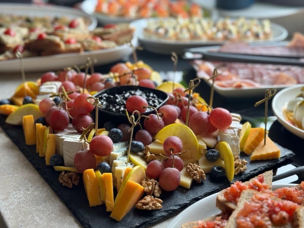 Una tabla de embutidos con diferentes quesos, frutas y frutos secos.