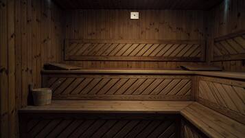 A wooden sauna with multiple benches and a small bucket.