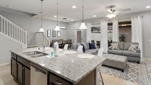A modern kitchen with granite countertops, a built-in dishwasher, and pendant lighting. - Spacious/ Near Disney/themed rooms/ private pool & game room/ resort grounds (Kissimmee)