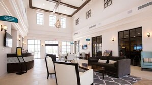 A spacious lobby with a reception desk, seating area, and a large window providing natural light. - Spacious/ Near Disney/themed rooms/ private pool & game room/ resort grounds (Kissimmee)