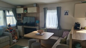Un salon confortable avec un téléviseur, une table en bois et un canapé.