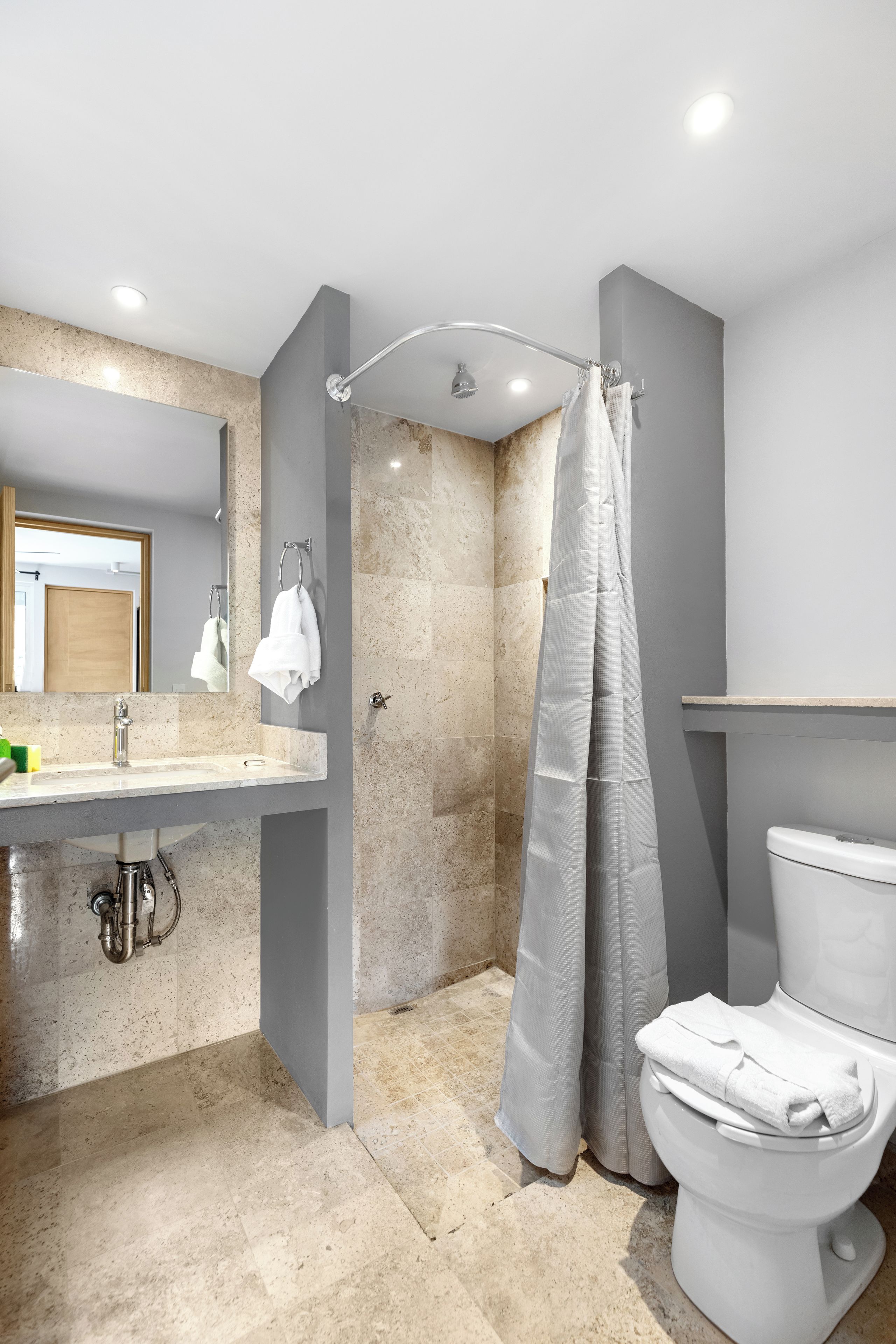 A modern bathroom with a shower, toilet, and sink.