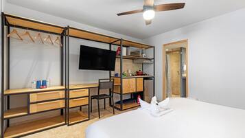 Une chambre d’hôtel moderne équipée d’un lit, d’un bureau, d’une chaise, d’une télévision et d’une kitchenette.