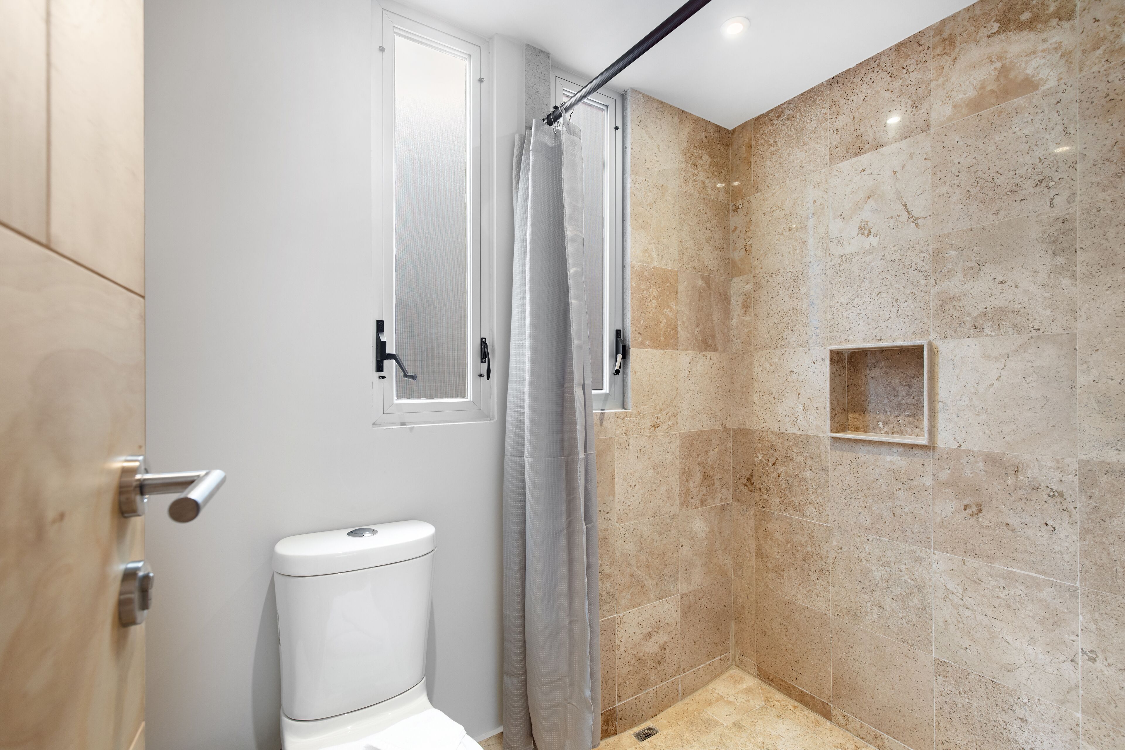 Une salle de bain moderne avec douche, toilettes et murs en marbre.