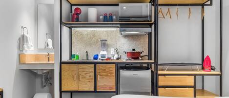 Una kitchenette compacta con microondas, tostadora y refrigerador pequeño.