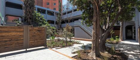 A courtyard with a wooden fence, a tree, and a building with multiple balconies.