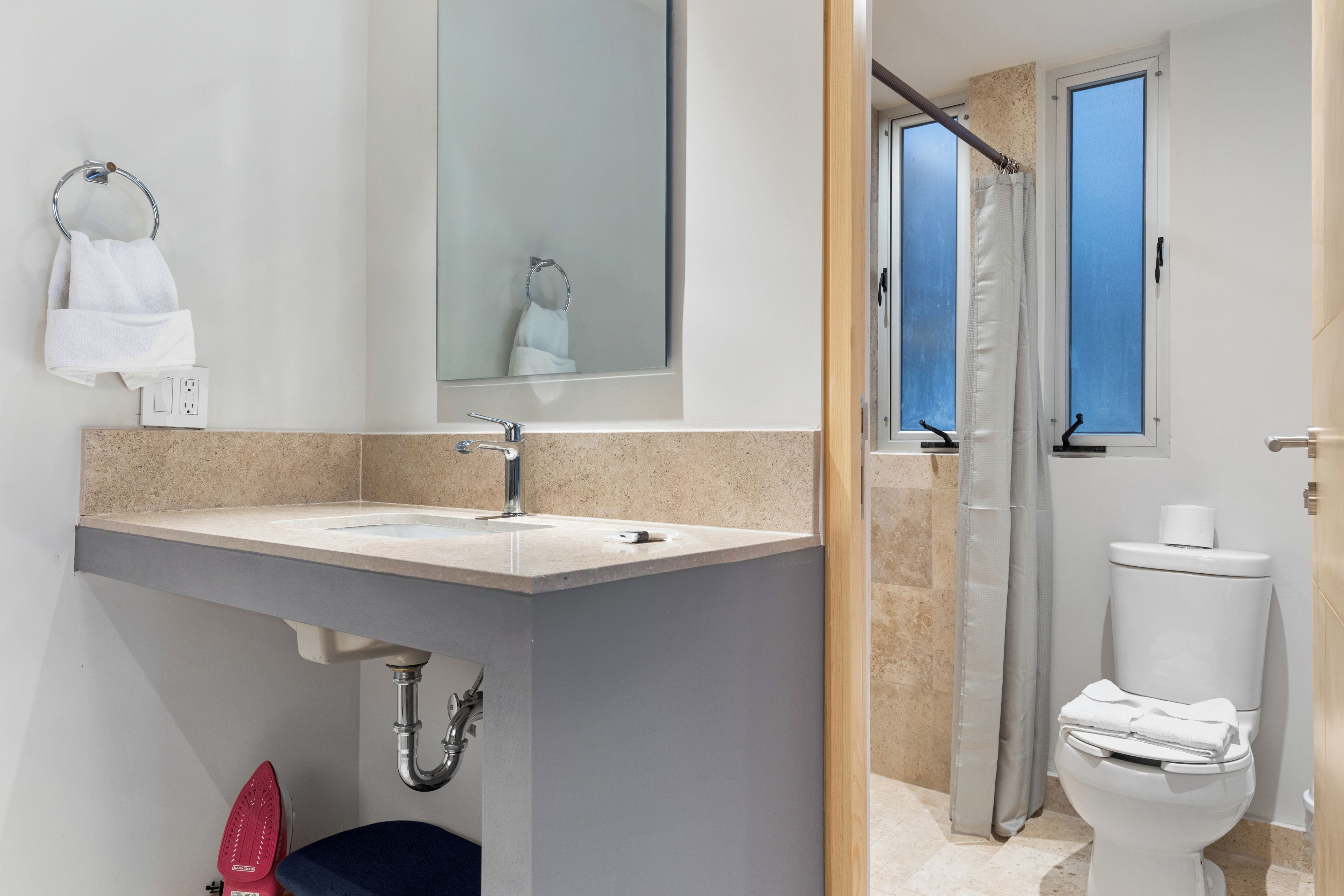 Un baño moderno con lavamanos, espejo e inodoro.