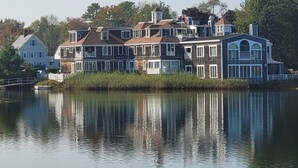 A large waterfront property with multiple buildings, including a prominent house with a balcony and a smaller structure with a flag.