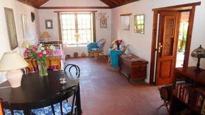 A cozy living room with a dining table, chairs, a bookshelf, and a door leading outside. - Casa  Grøn (CN)