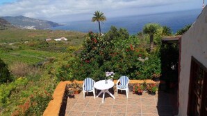 A patio with two chairs and a table, overlooking a coastal landscape with vineyards and a view of the ocean. - Casa  Grøn (CN)