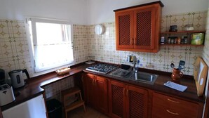 Eine Küche mit Holzausstattung, einem Gaskochfeld, einer Spüle und einem Fenster.