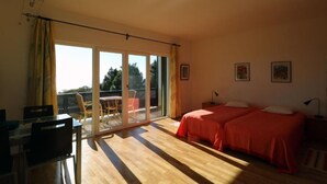 Un dormitorio con dos camas, un balcón y una zona de comedor.