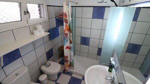 Un baño con inodoro, lavabo y zona de ducha.