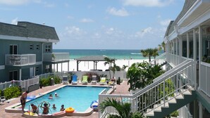 A pool area with a view of the beach, including a pool, lounge chairs, and a staircase. - Beachfront Condo with Private Balcony - Beachfront Resort- Pool - Kitchen  (St. Pete Beach)