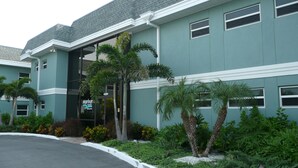 A building with a green facade, multiple windows, and a parking lot. - Beachfront Condo with Private Balcony - Beachfront Resort- Pool - Kitchen  (St. Pete Beach)