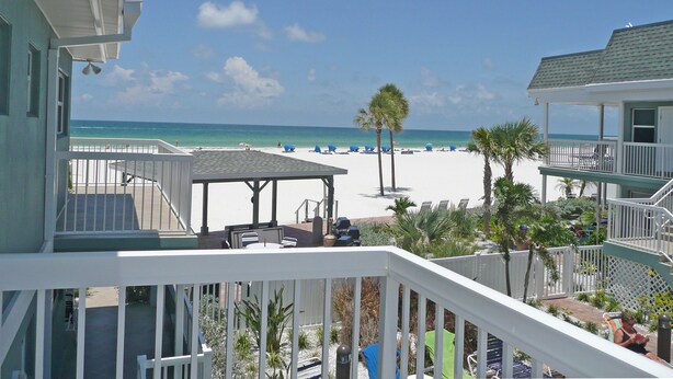 A beachfront property with a covered patio, a pool, and a view of the beach. - Beachfront Condo with Private Balcony - Beachfront Resort- Pool - Kitchen  (St. Pete Beach)