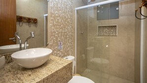 A bathroom with a granite countertop, a white sink, a mirror, and a glass-enclosed shower. - R. Virgínia 48 (Búzios)