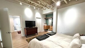 A bedroom with a large bed, a dresser, a television, and a mirror. - The Quarters | Suite 1 (Grafton)