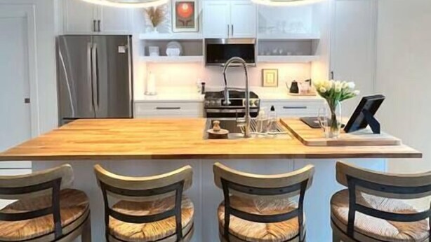 A modern kitchen with a central island, bar stools, stainless steel appliances, and pendant lighting. - The Quarters | Suite 3 (Grafton)