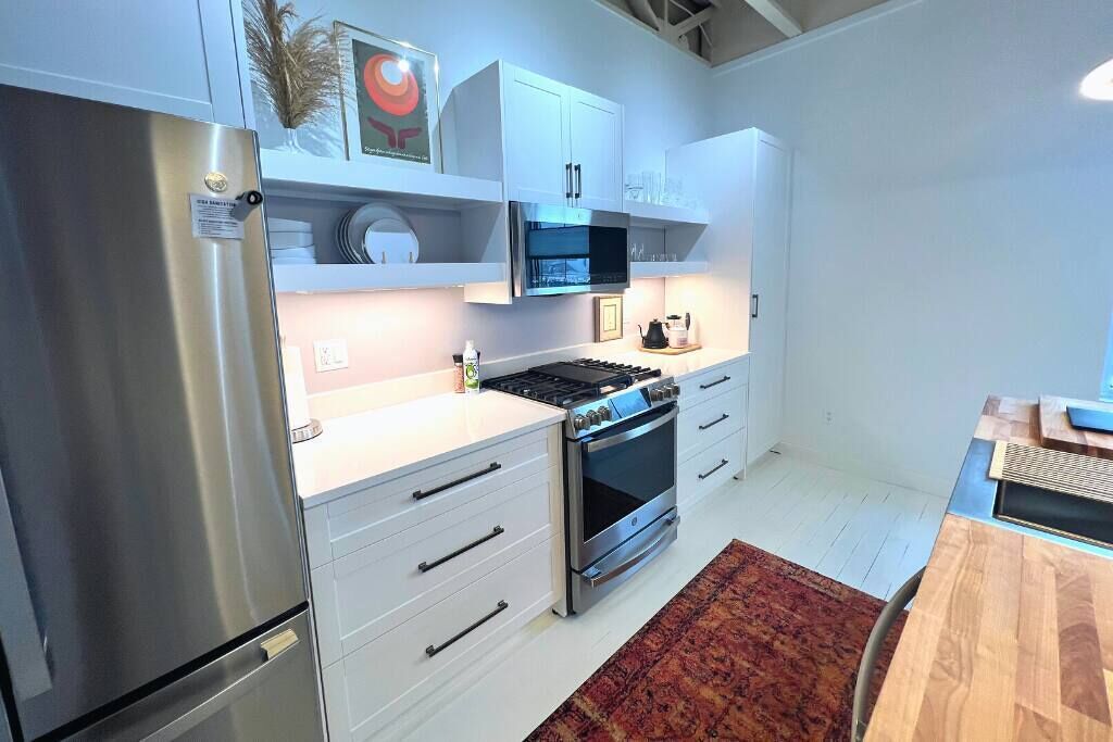 Una cocina moderna con armarios blancos, electrodomésticos de acero inoxidable y una mesa de comedor de madera.