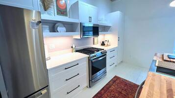 Una cocina moderna con armarios blancos, electrodomésticos de acero inoxidable y una mesa de comedor de madera.