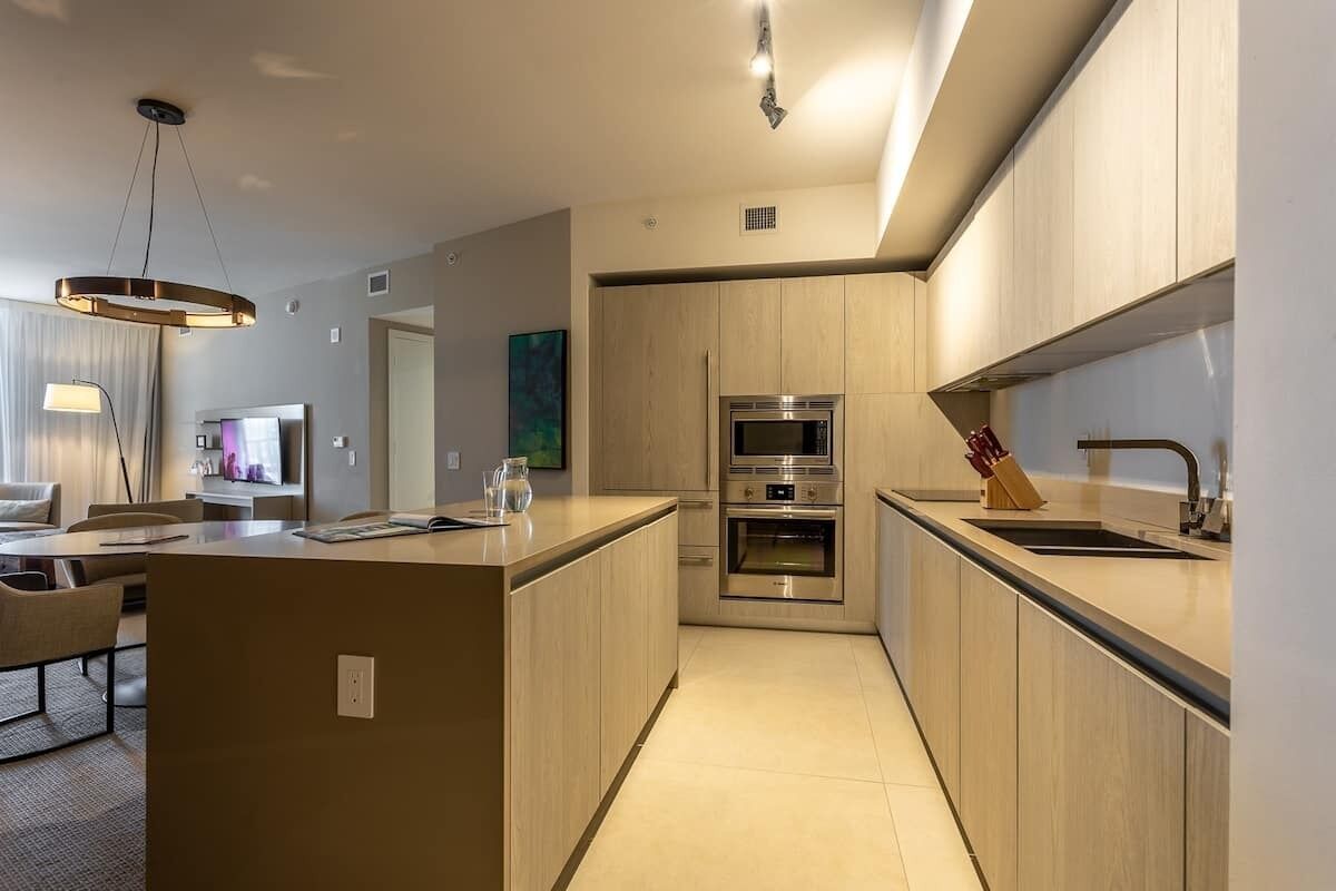 A modern kitchen with a central island, built-in oven, and stainless steel appliances.