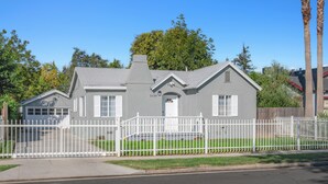 Una casa de dos pisos con valla de piquetes blancos, un garaje y un césped cuidado.