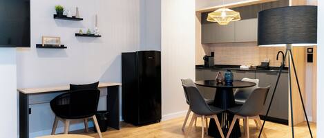 Una cocina moderna con un refrigerador negro, una mesa de comedor con sillas y una lámpara colgante.
