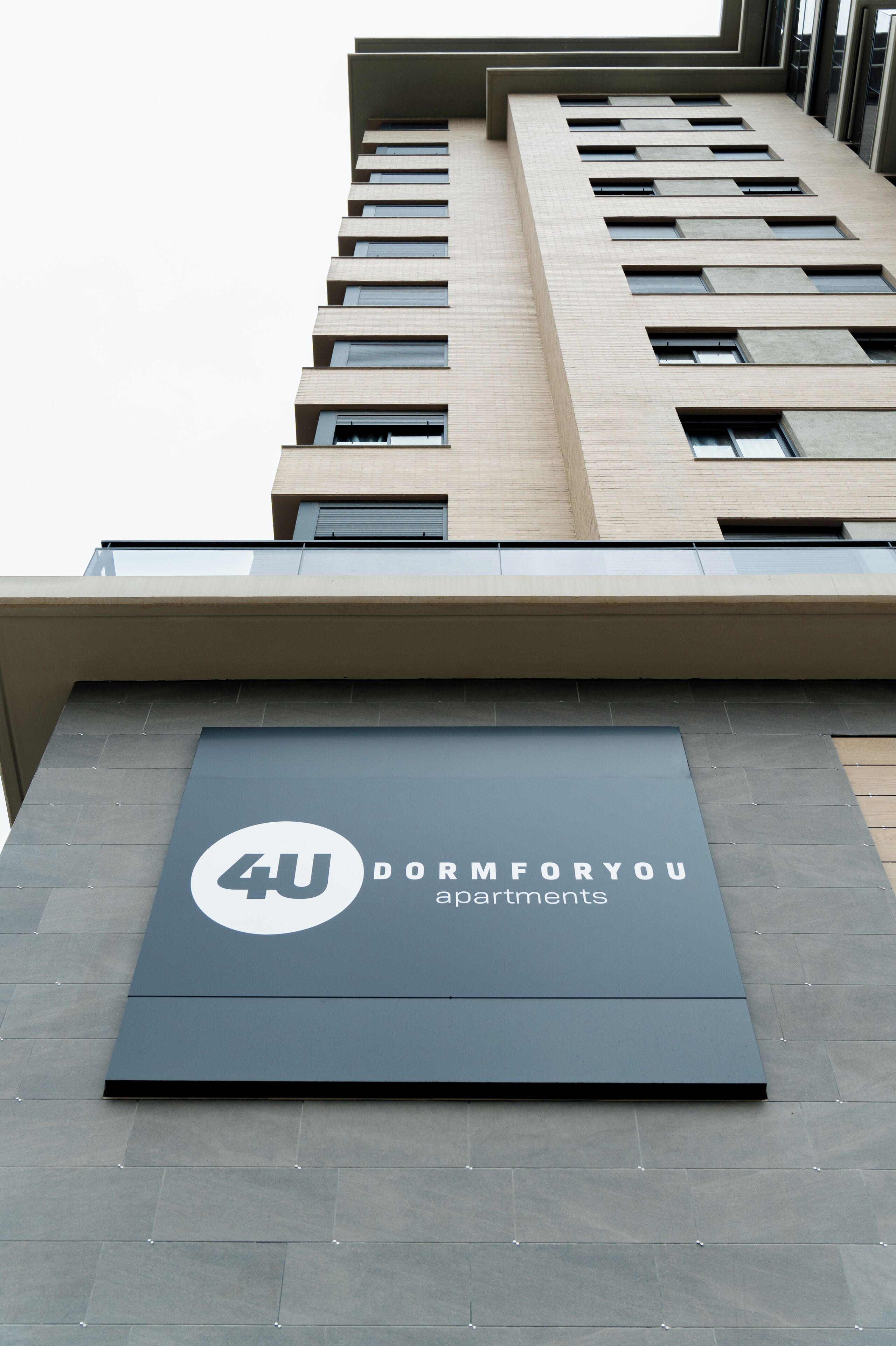 Un edificio moderno con un letrero que dice '4U Dormitory Apartments'.