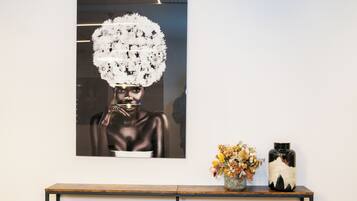 A framed artwork on a wall, a wooden console table with a vase of dried flowers, and a ceramic vase with a black and white design.