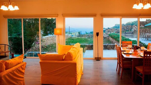 Ein geräumiges Zimmer mit großem Fenster, einer Essecke und einem Sofa.