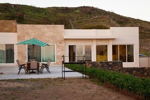 Une maison moderne dotée d’un patio, d’un espace salon extérieur et offrant une vue sur une colline.