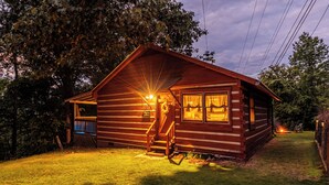 Une cabane en bois avec un porche, un foyer et une pelouse bien entretenue.