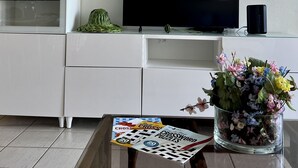 A modern living room with a flat-screen TV, white cabinetry, and a coffee table with a crossword puzzle magazine. - Family friendly place for those looking for adventure, beach, and great food! (Ceiba)