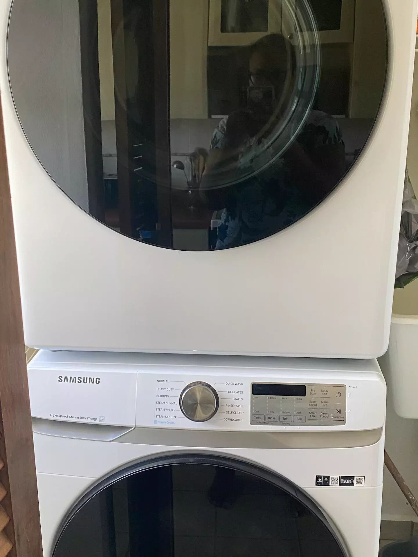 A stacked washer and dryer unit with a control panel displaying various settings.