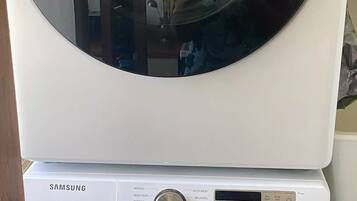 A stacked washer and dryer unit with a control panel displaying various settings.