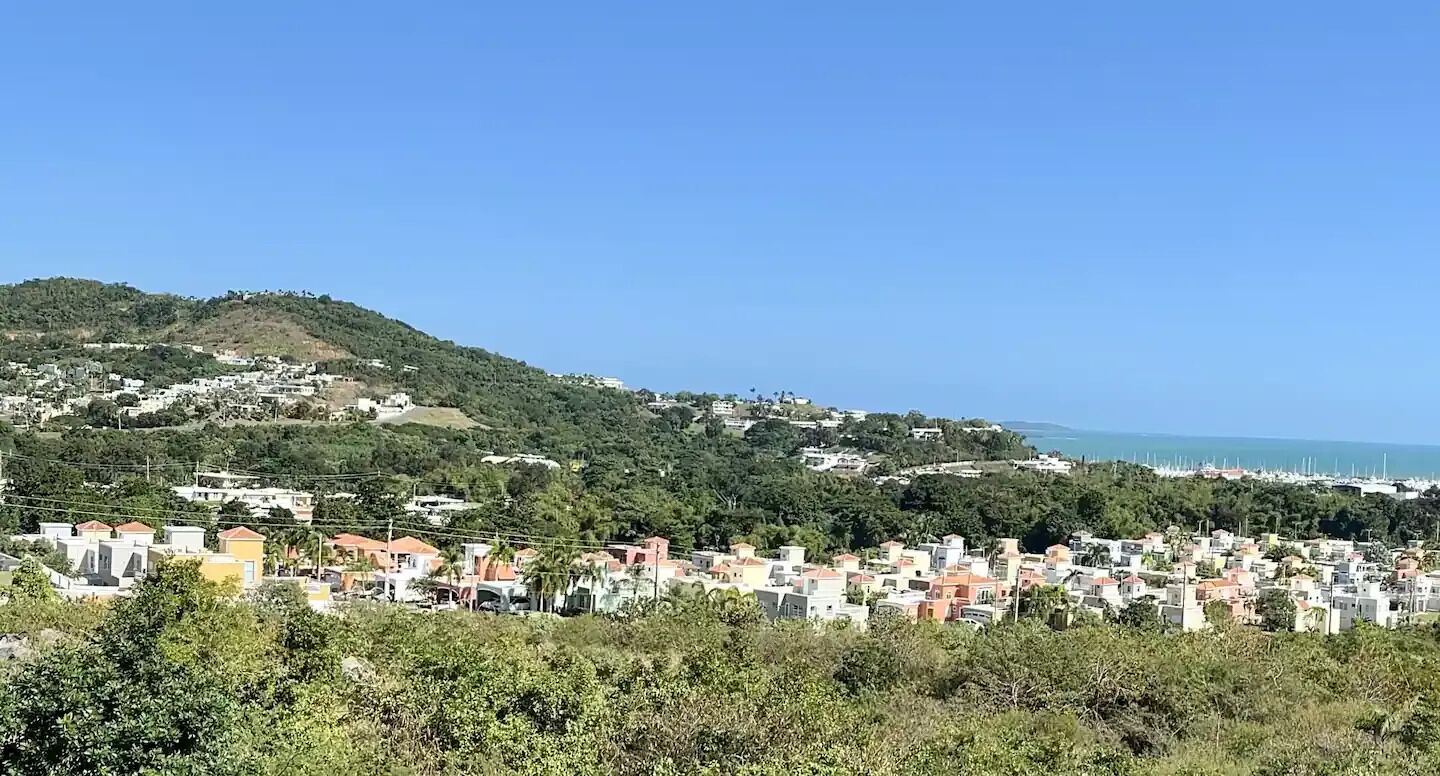 Eine Küstenstadt mit Gebäuden an einem Hügel, einem klaren Himmel und Blick auf das Meer.