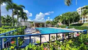 A pool area with a blue pool, lounge chairs, and palm trees. - Family friendly place for those looking for adventure, beach, and great food! (Ceiba)