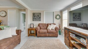 A living room with a brown leather sofa, a wooden coffee table, and a TV stand with shelves. - Oklahoma Home Near Lake w/ Patio, Grill & Chiminea (Fort Cobb)